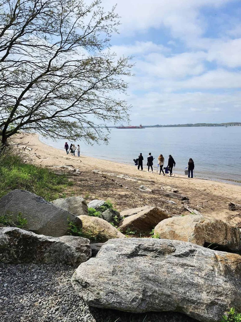 Serene lakeside beach scene with people walking and enjoying nature, ideal for outdoor adventure and relaxation.