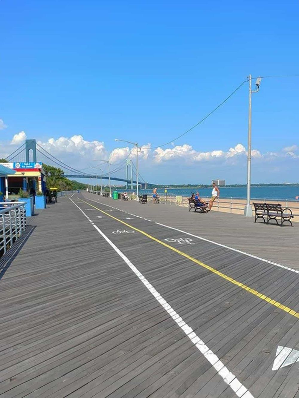 A scenic pier with bike lanes, benches, and a view of the bridge over water, perfect for relaxing and walking.