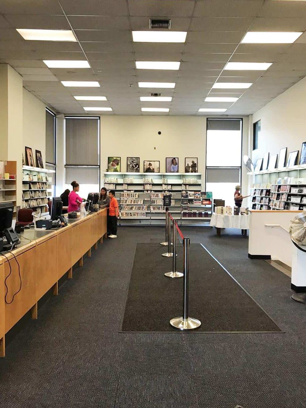 Bright library interior with front desk and bookshelf, people browsing, quiet study environment, QuestForDirections location.