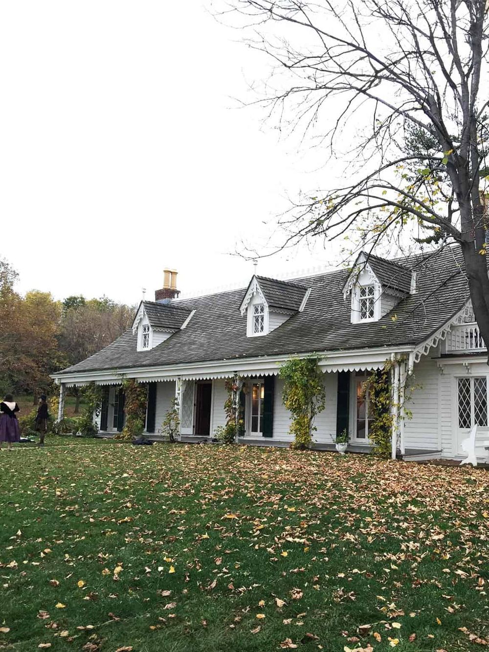 Charming white Victorian house with autumn leaves outside, perfect for scenic house tours.