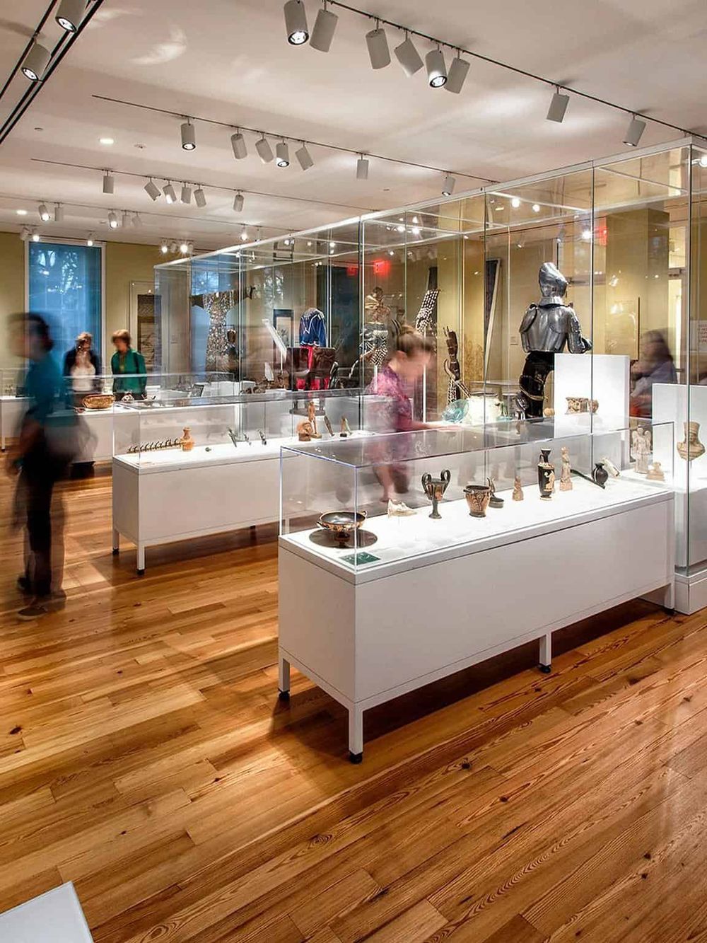 Ancient artifact display at a museum, showcasing pottery and sculptures with visitors exploring exhibits.