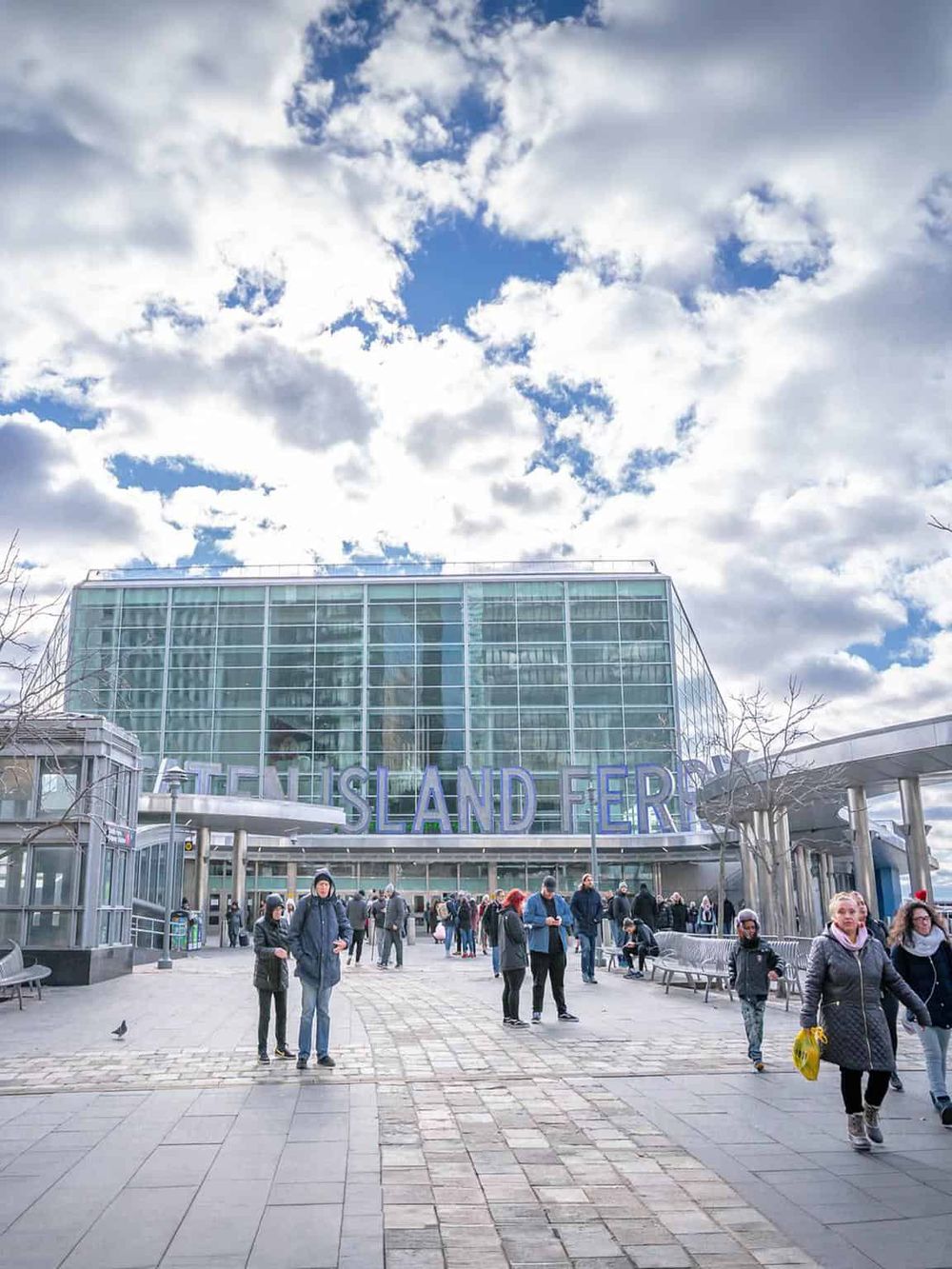 Modern ferry terminal with visitors and cloudy sky, emphasizing travel and transportation.