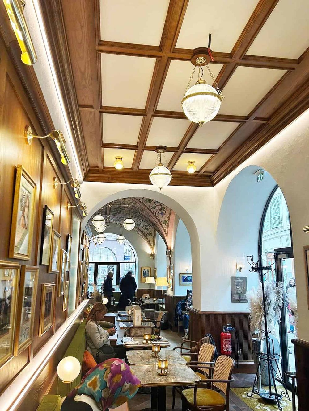 Cozy cafe interior with elegant wooden ceiling, ambient lighting, artwork, and a welcoming atmosphere.