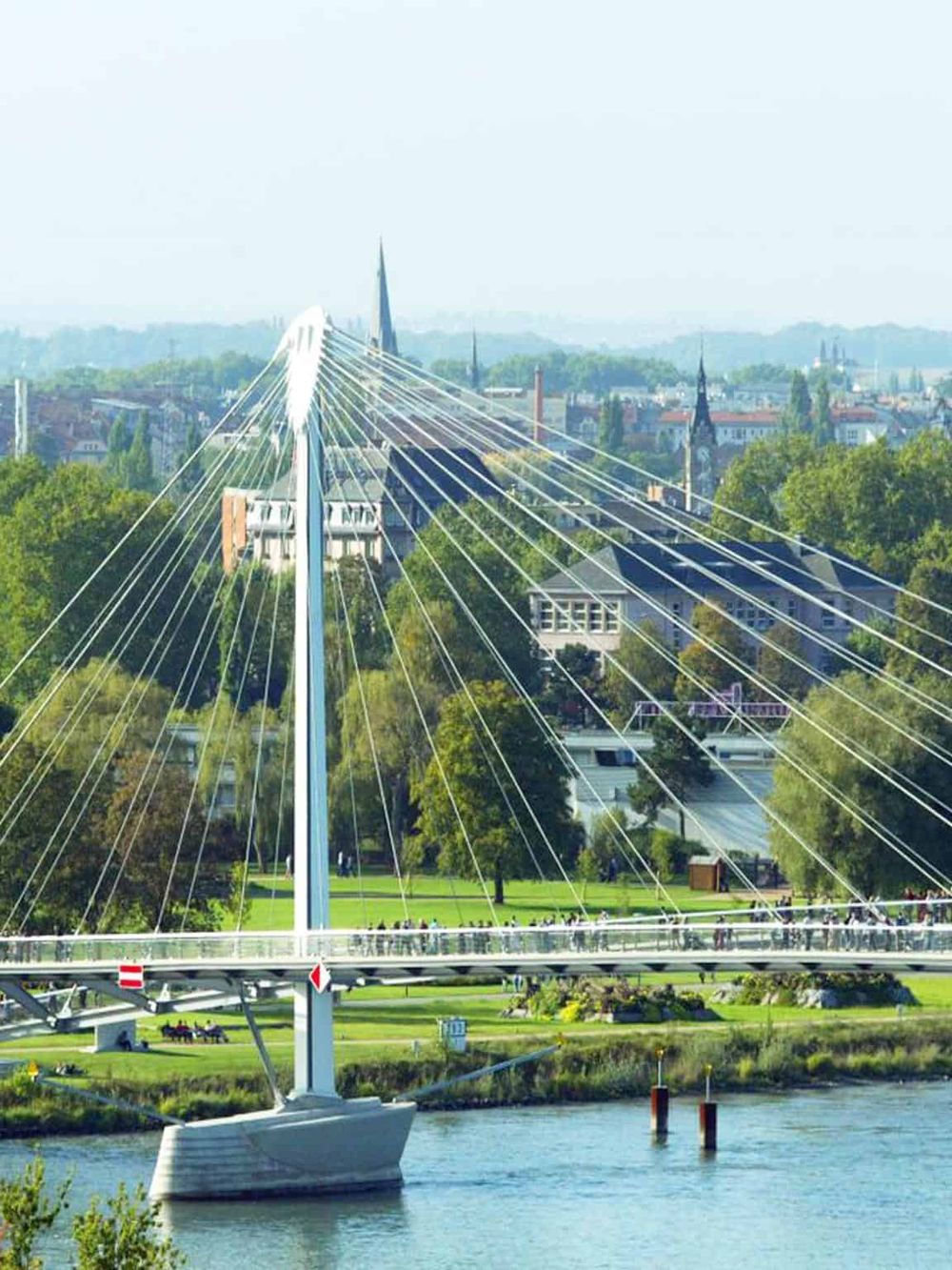 Modern suspension bridge over water with cityscape background, efficient navigation, and travel solutions.