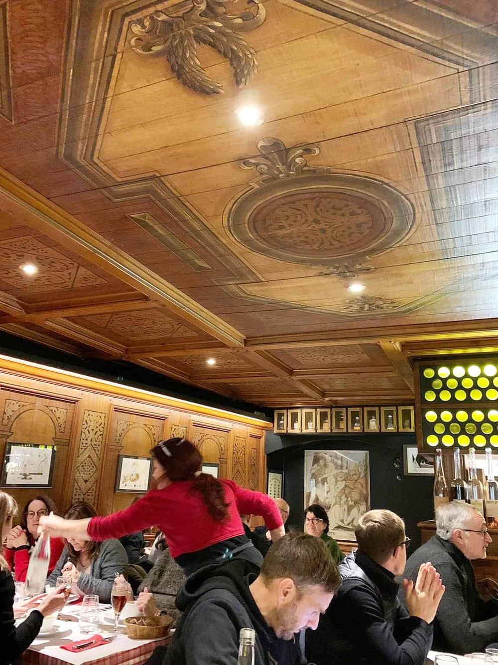 Vibrant restaurant interior with wooden ceiling and group dining, showcasing social gathering, cozy ambiance, and classic decor.