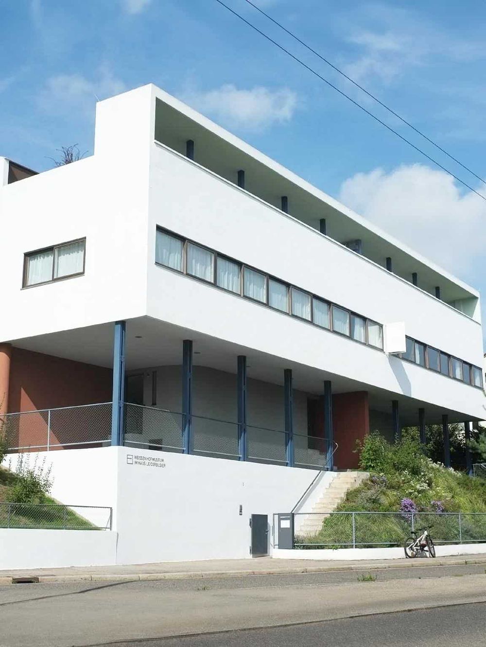 Modern architectural building with white facade, large windows, and outdoor space, representing innovative design.