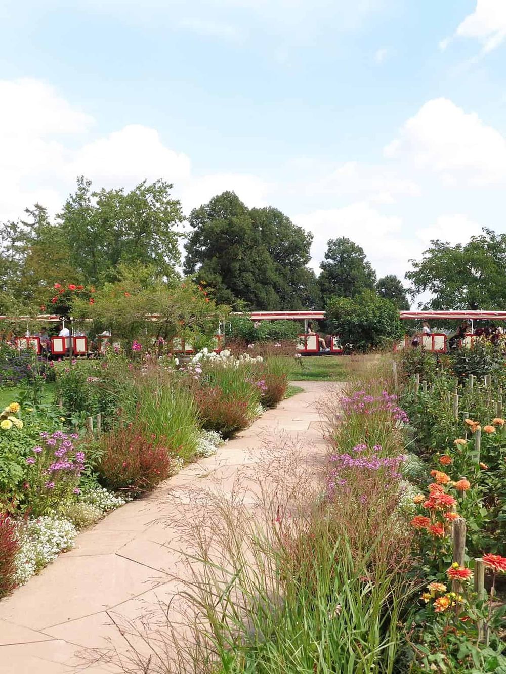 Colorful garden pathway at Quest for Directions amusement park with scenic train rides in the background.