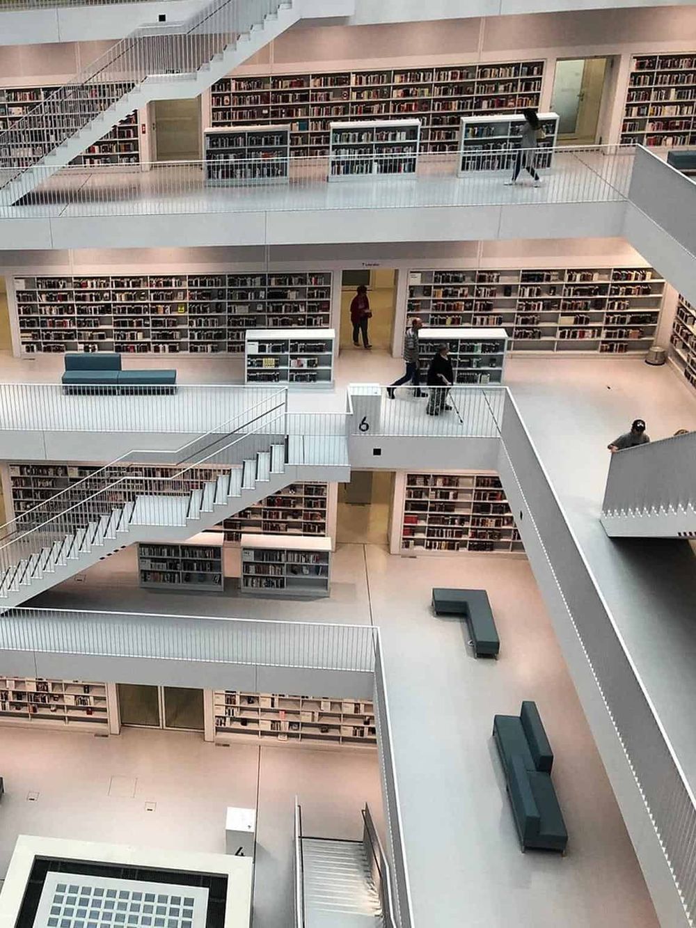 Bright multi-level modern library interior with extensive bookshelves and seating areas.