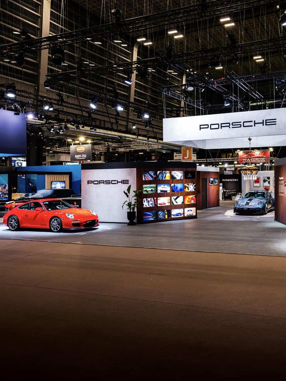 Stylish Porsche car exhibit at a luxury auto show within a modern exhibition hall.