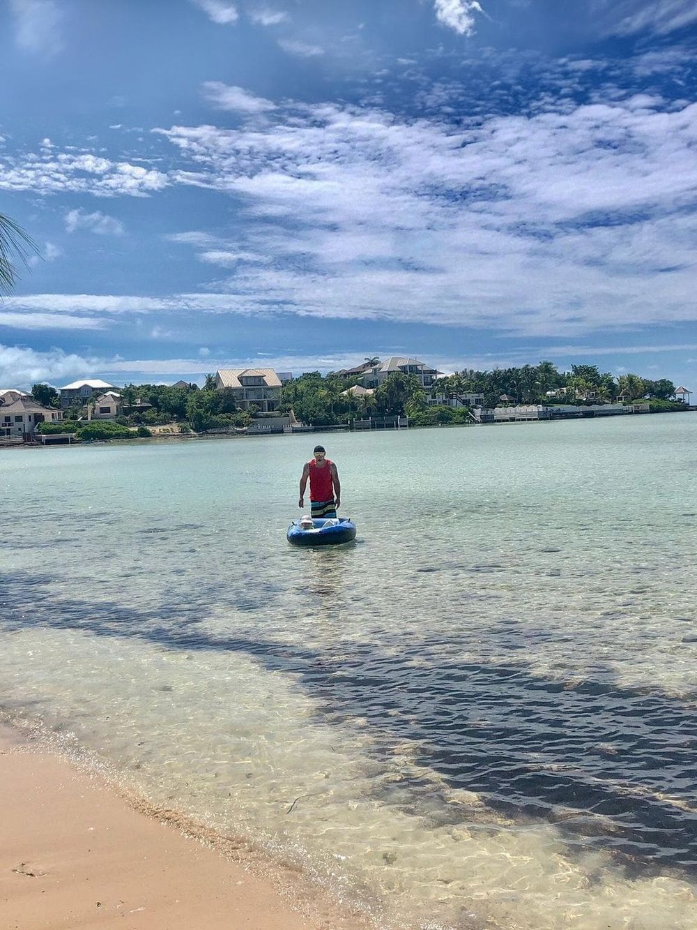 Serene coastal scene with paddleboarder, calm waters, and seaside homes, perfect for outdoor adventure and water sports.