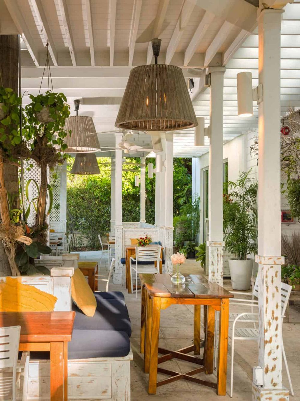 Cozy outdoor dining area with lush greenery, rustic wooden furniture, and tropical plants for relaxing meals.