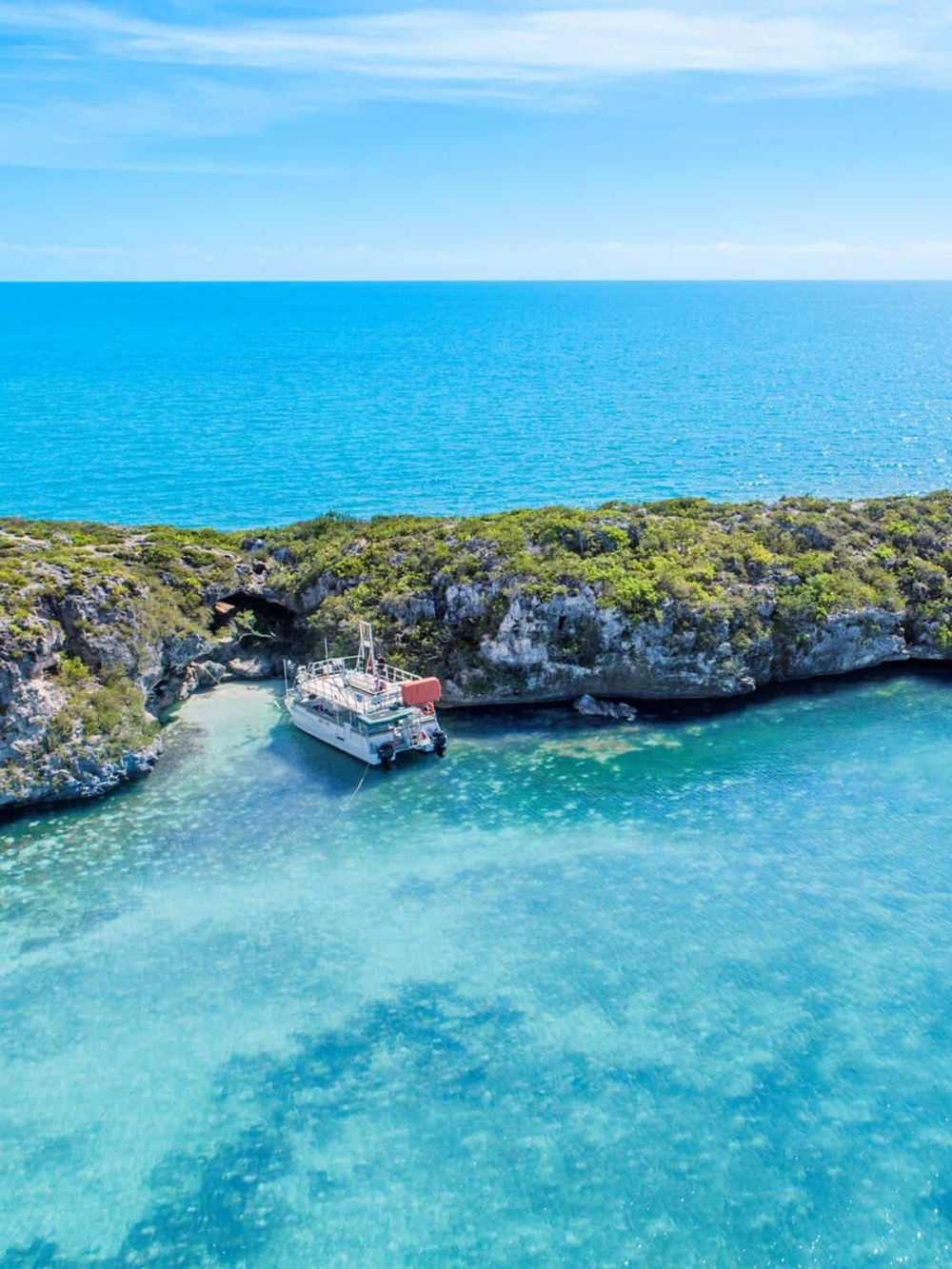 Serene coastal cove with a anchored boat and lush greenery, ideal for scenic island adventures.