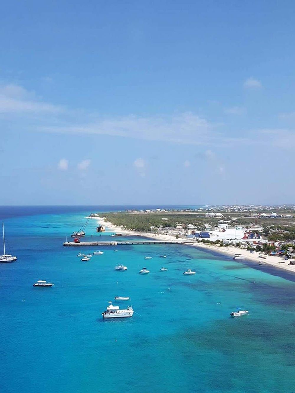 Vibrant tropical beach with turquoise waters, boats, and coastal development, ideal for travel and vacation planning.