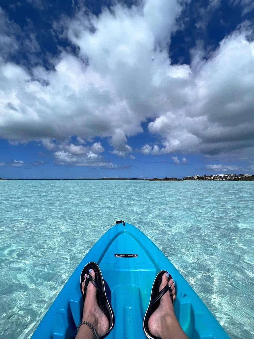 Bright blue kayak on crystal clear water under cloudy sky, ideal for outdoor adventures.
