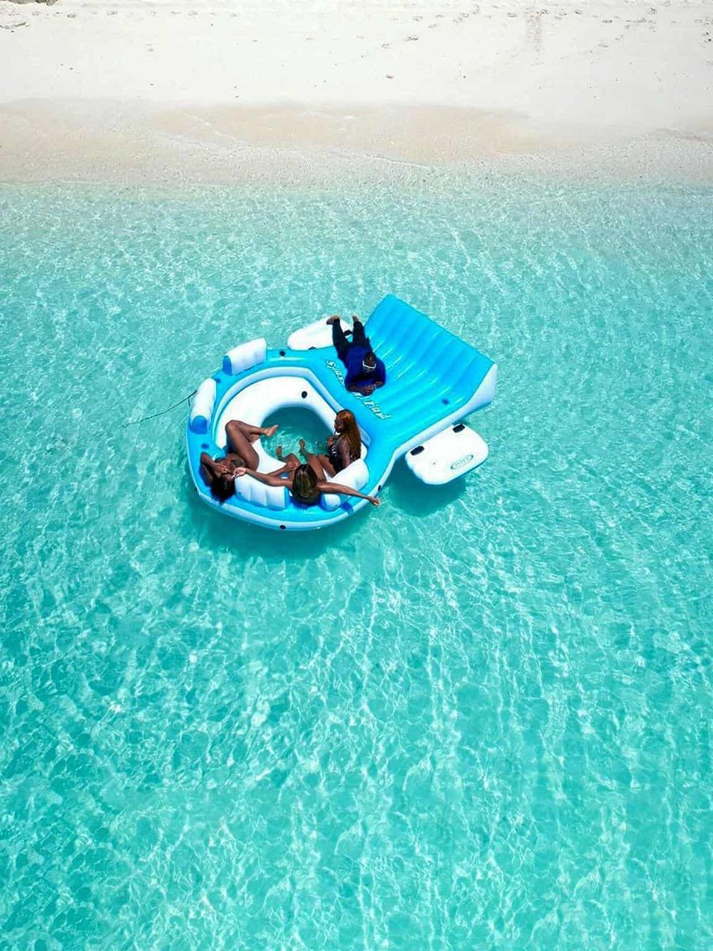 Inflatable boat with people relaxing on clear turquoise water, tropical beach scene, summer vacation, tranquil sea.