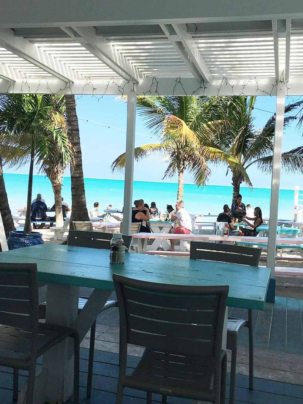 Vibrant seaside restaurant with ocean view, palm trees, and outdoor dining, perfect for a tropical vacation experience.