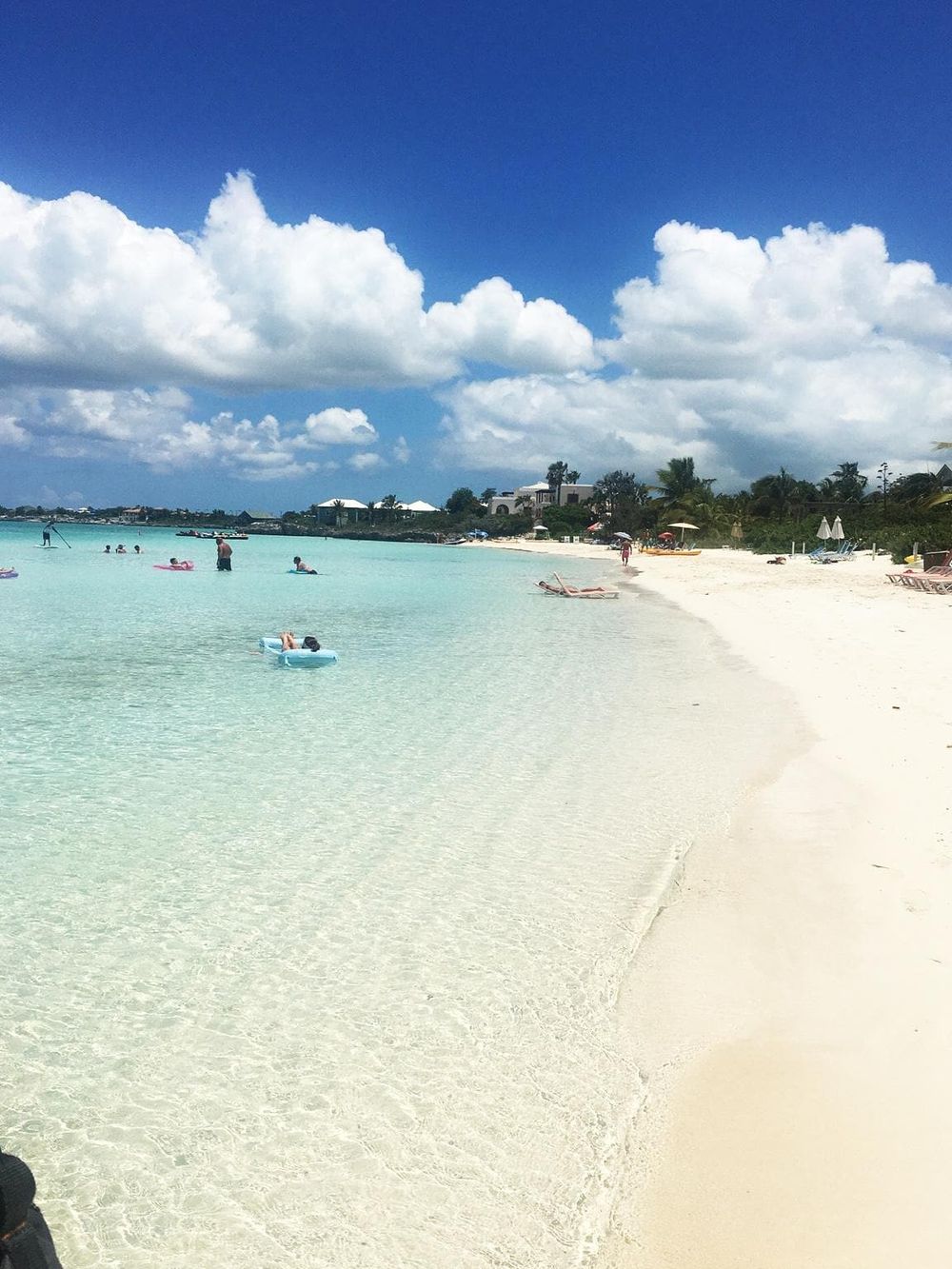 Relaxing beach scene with turquoise waters, ocean swimmers, and sunny skies - ideal for travel and vacation planning.
