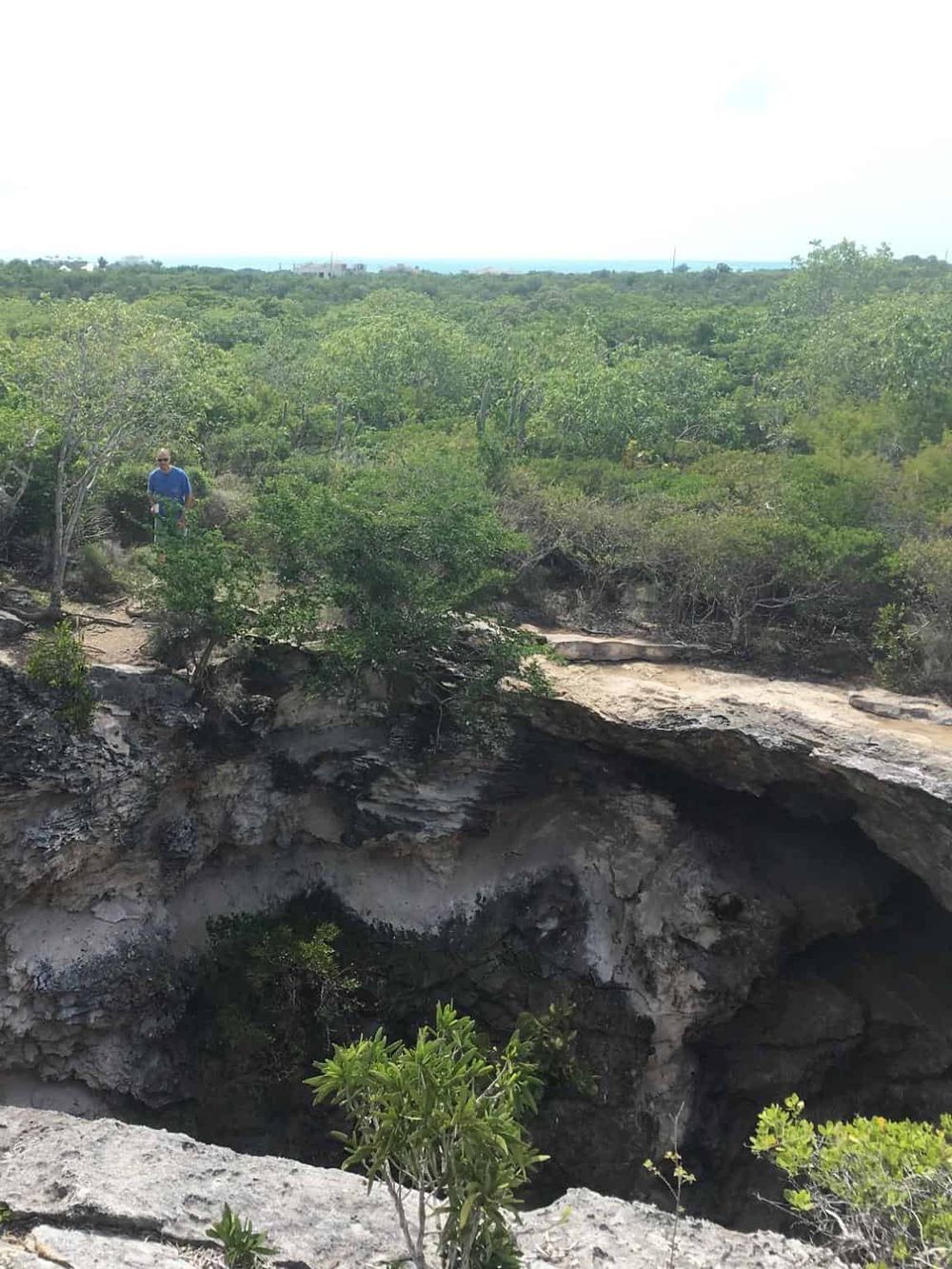 Vast natural landscape with a person exploring rocky terrain and lush greenery, perfect for adventure and nature discovery.