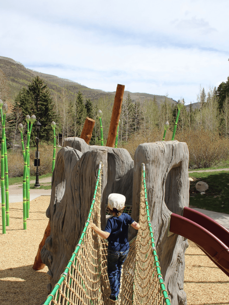 Colorful outdoor playground structure with a bridge and slide in a park setting.