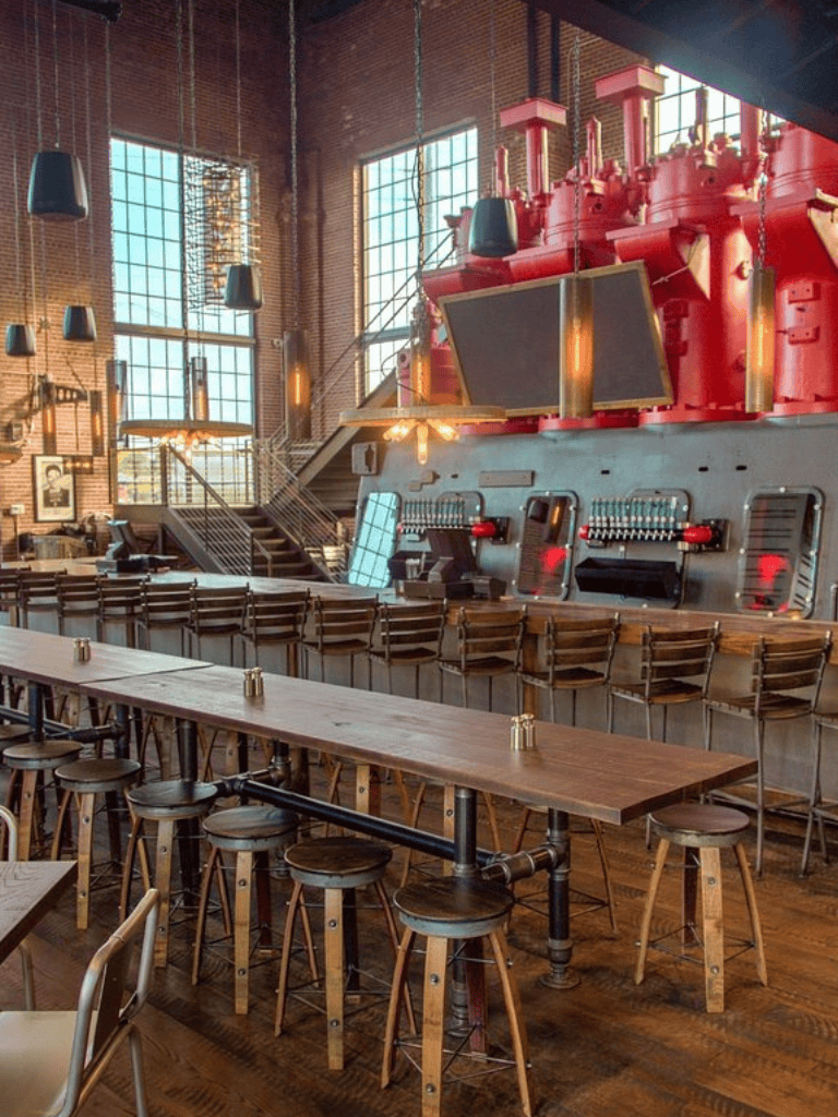 Industrial bar interior with large windows, high ceilings, and vintage decor for social gatherings.