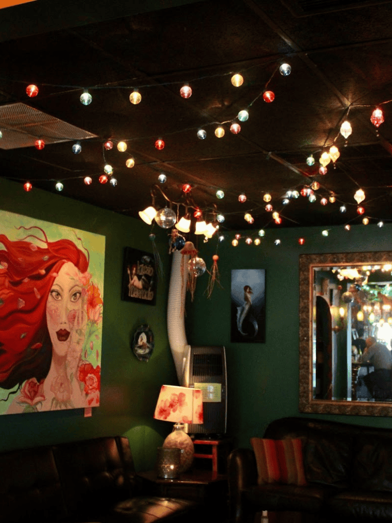 Colorful string lights illuminating cozy, artistic indoor space at QuestForDirections venue.