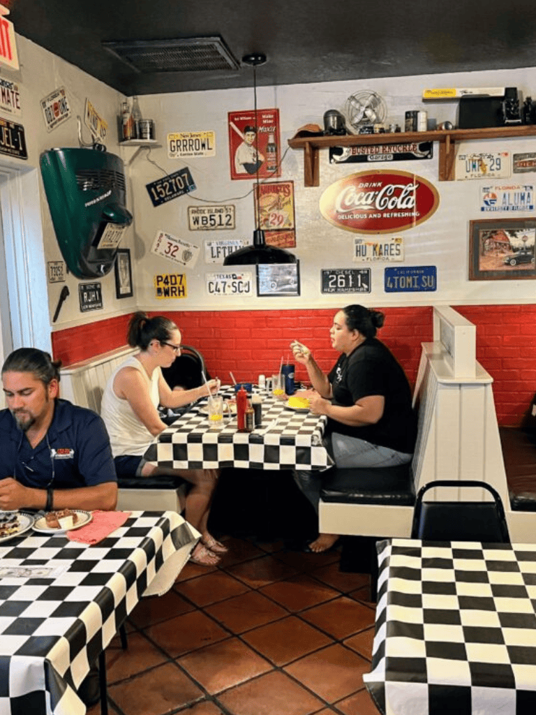 Cozy diners at a 1950s-themed restaurant with vintage license plates and Coca-Cola decor.