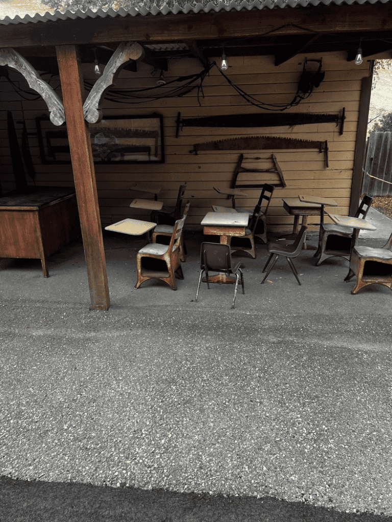 Worn vintage school desks and chairs in rustic outdoor classroom setting.
