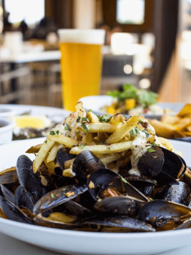 Steamed mussels with fries and creamy sauce at a cozy restaurant.