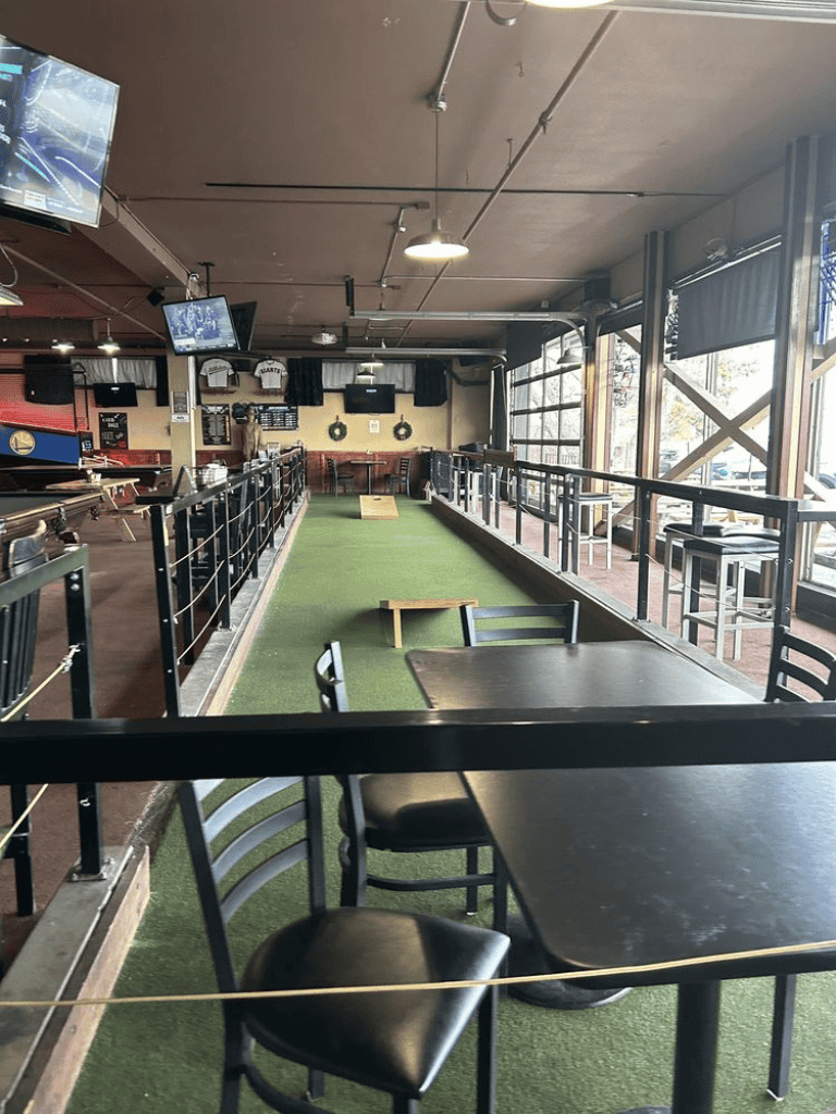 Playing golf indoors at QuestForDirections entertainment venue. A fun activity space with artificial turf and tables.