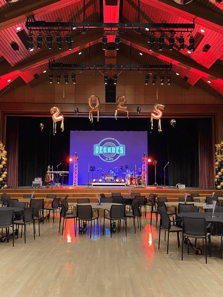 Stage setup for a 2025 event with musical instruments, balloons, and decor at QuestForDirections venue.