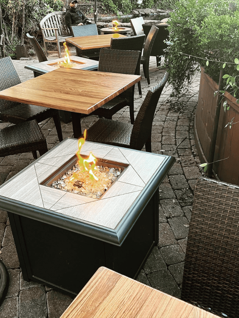 Cozy outdoor patio with fire pits and wicker chairs at QuestForDirections restaurant.