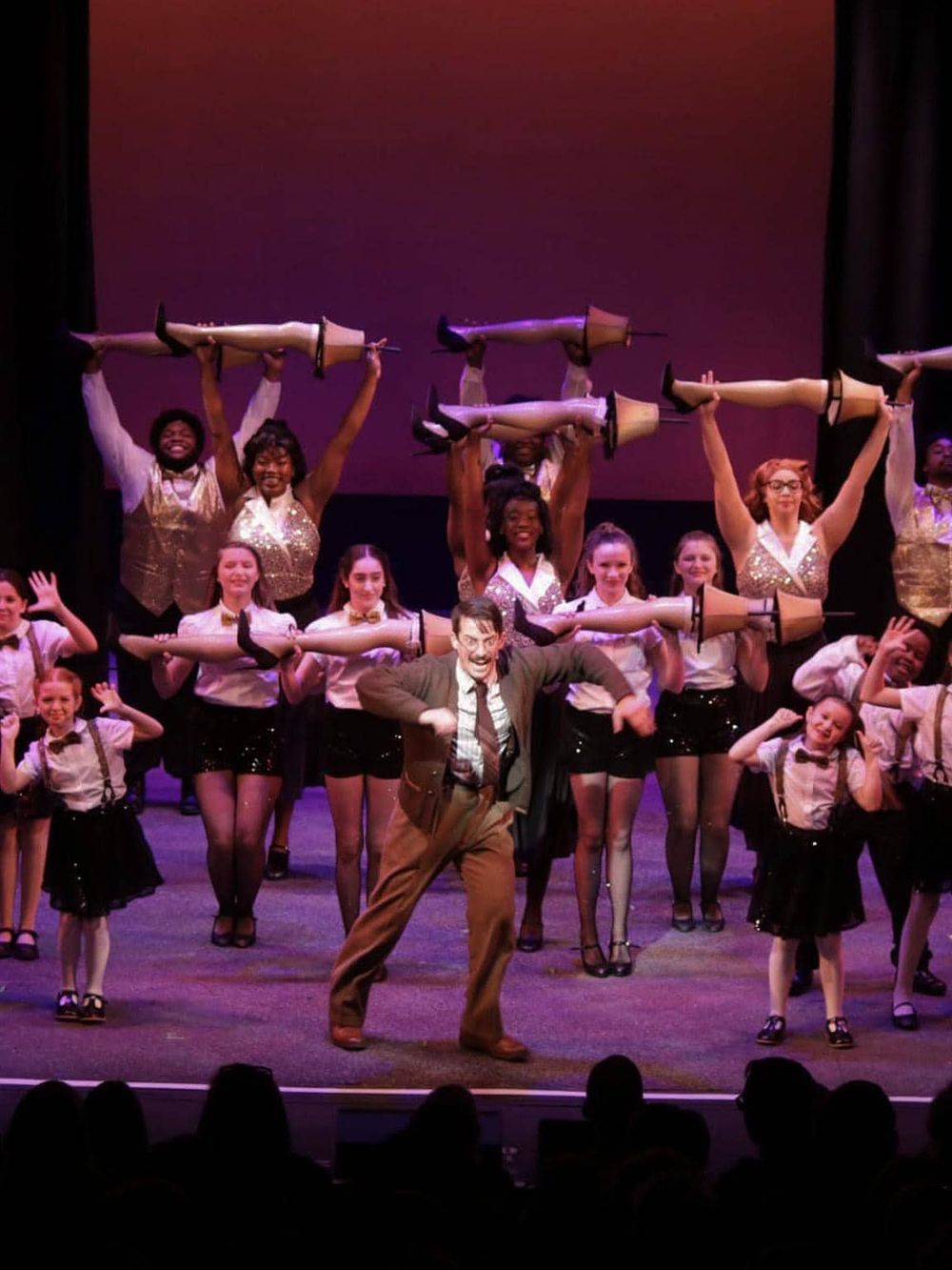 Dance performance by diverse group of students with props on stage, showcasing entertainment and youth culture.