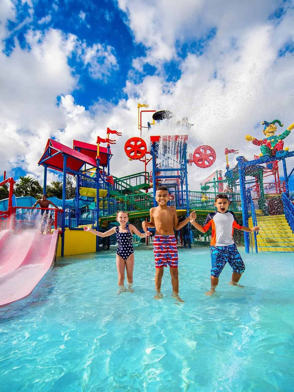 Colorful water park with kids enjoying water slides and playful attractions under a bright blue sky.