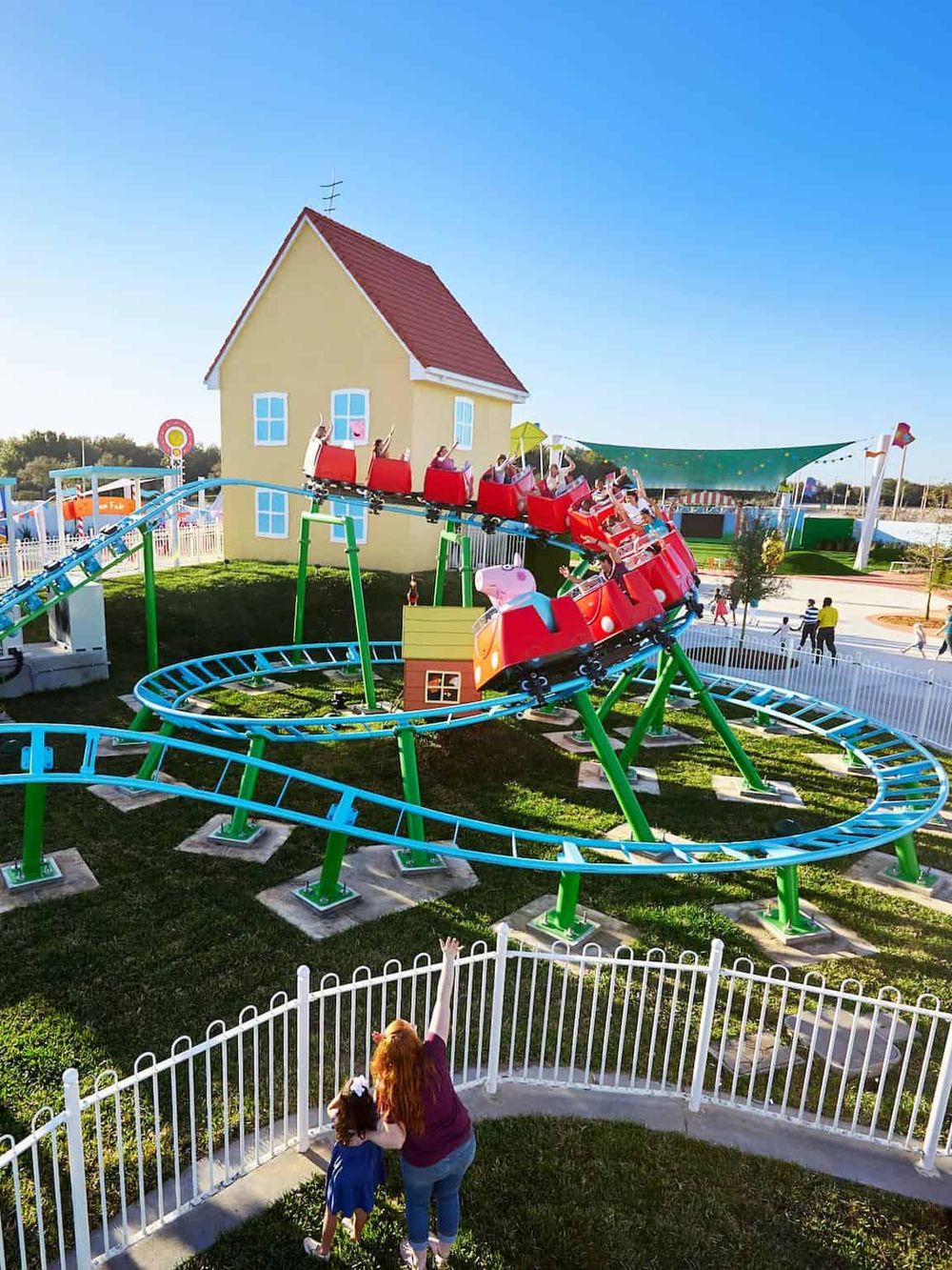 Amusement park roller coaster ride with children and family, fun outdoor adventure, family entertainment.