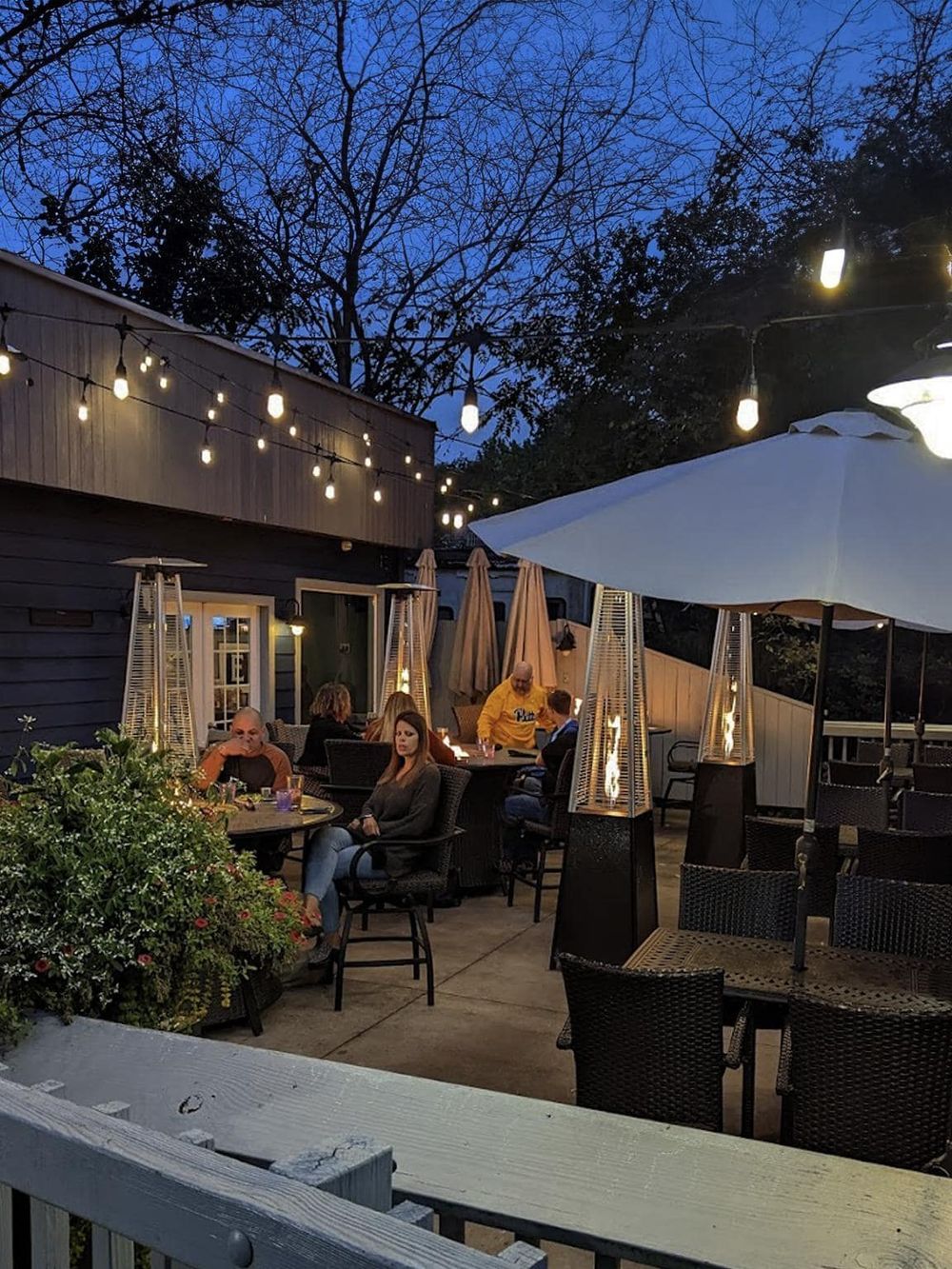 Outdoor dining with string lights and heaters at QuestForDirections restaurant.