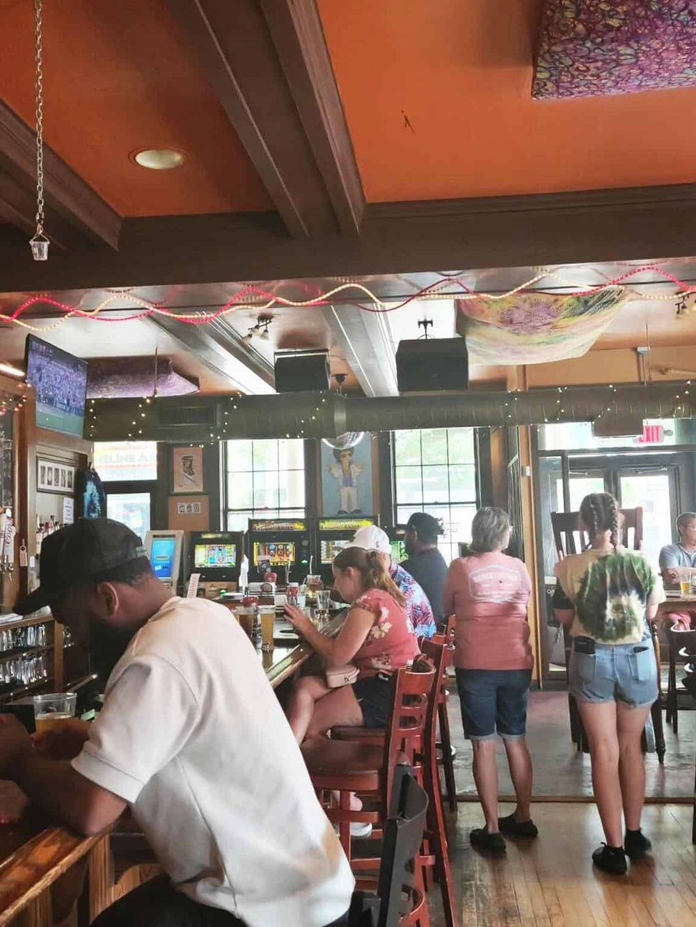 Busy sports bar with patrons watching a game on TV, enjoying drinks, and socializing indoors.
