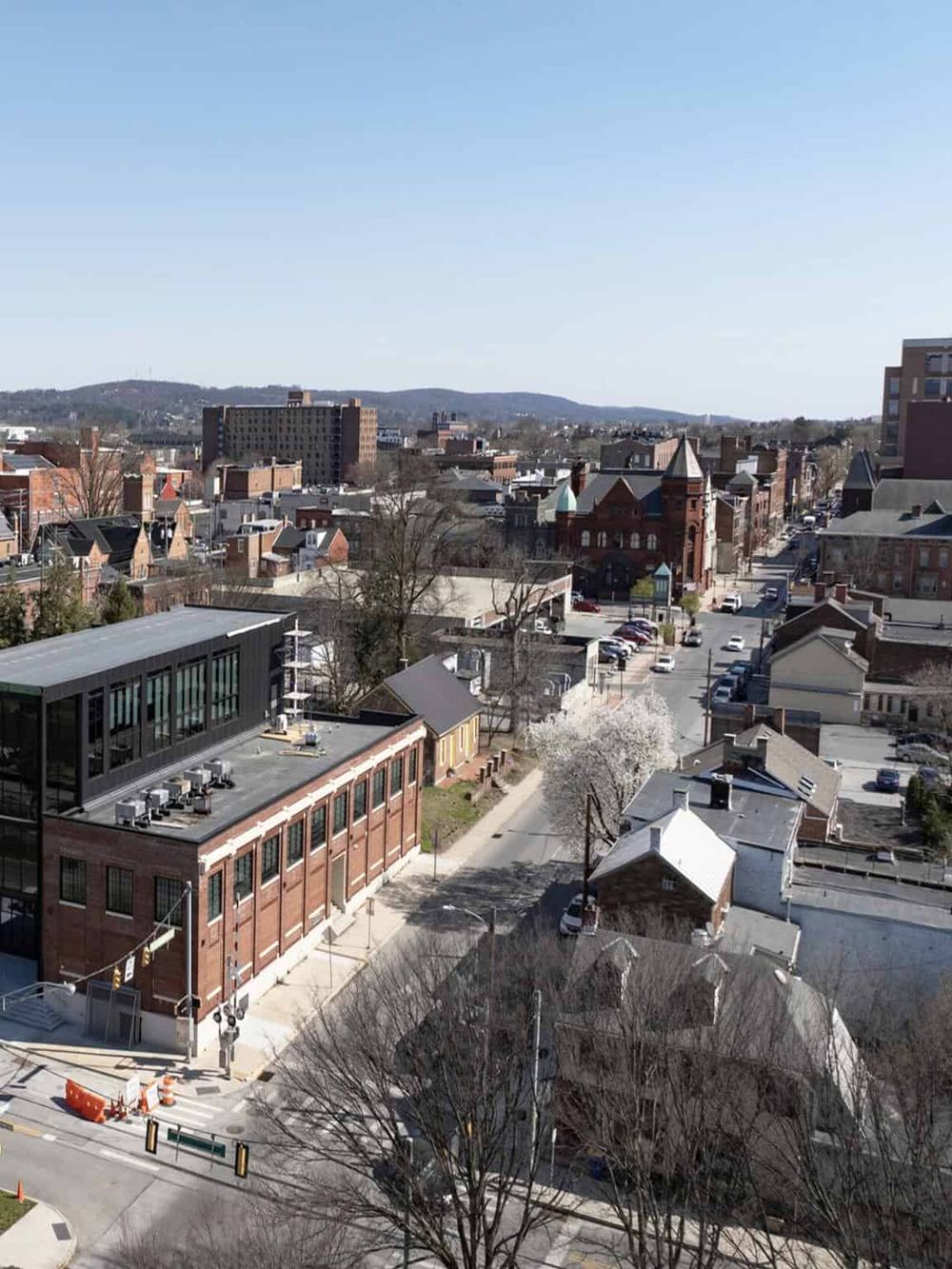 Vibrant cityscape featuring historic buildings, modern architecture, and scenic hills in the background.