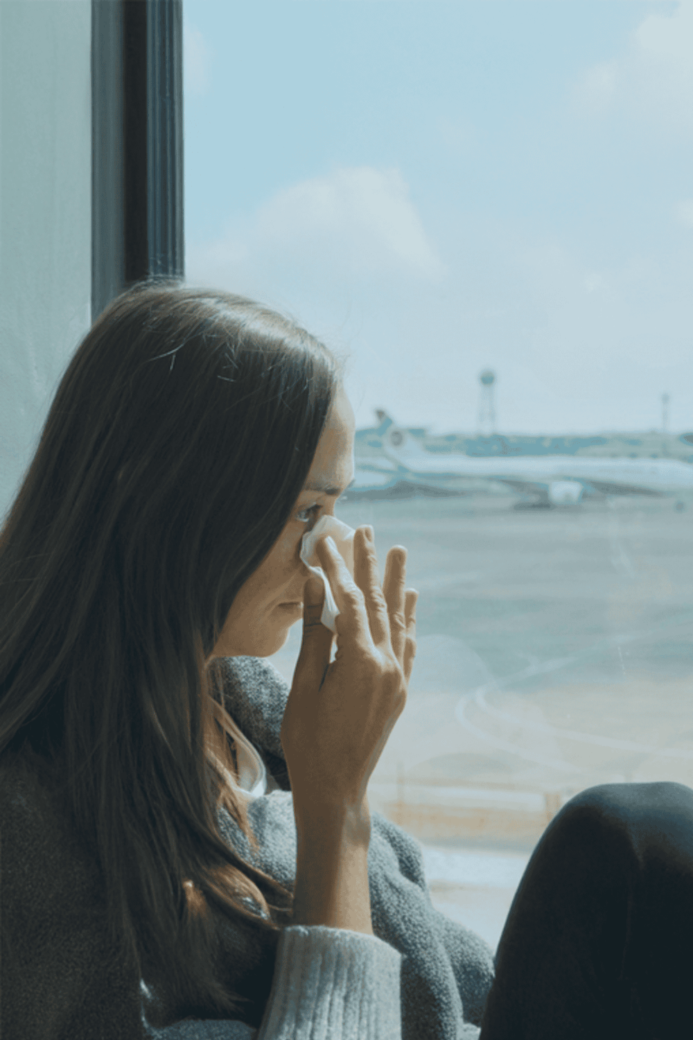 Woman wiping tears at airport window, travel stress, emotional flight moments, QuestForDirections imagery.