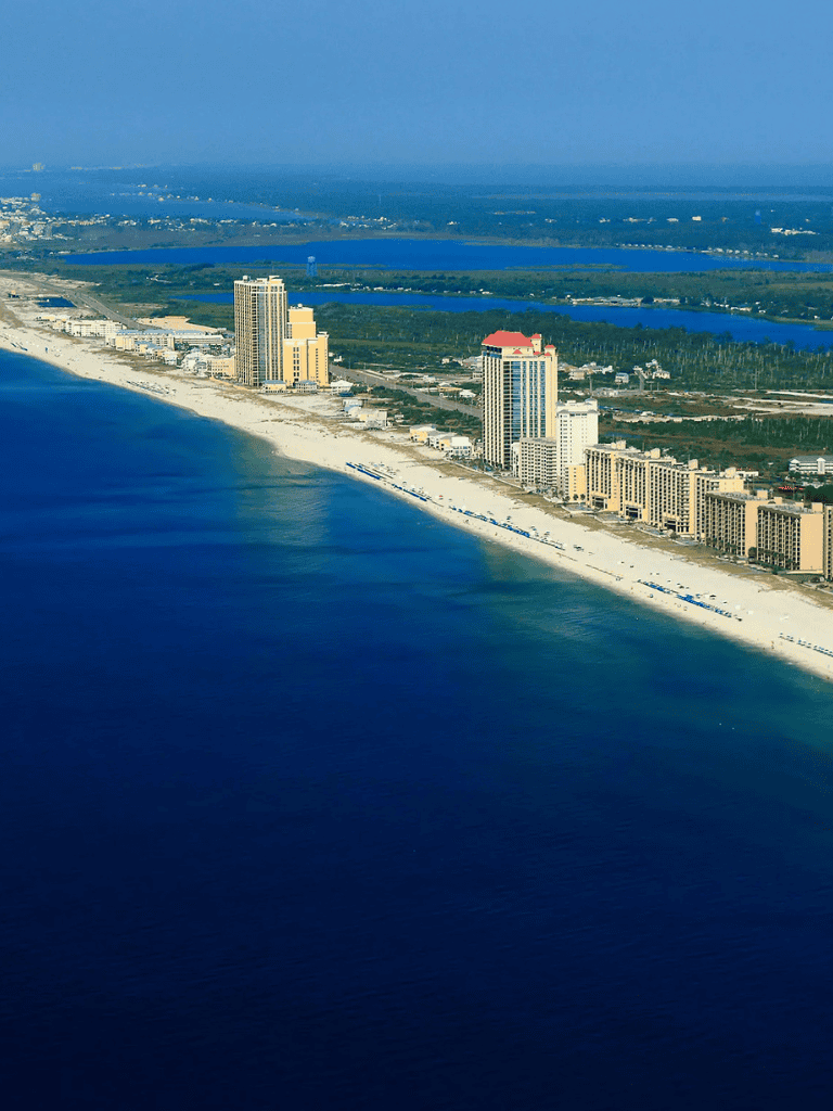 Aerial view of beachfront cityscape with high-rise hotels and sandy beaches on the Gulf Coast.