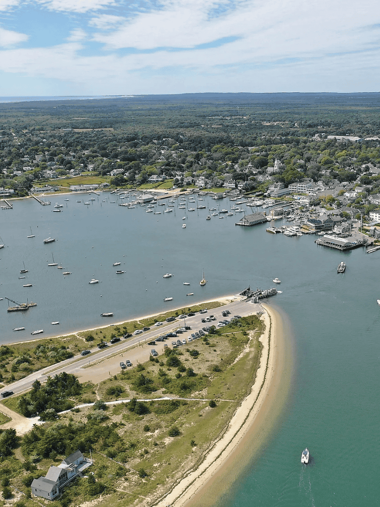 Scenic coastal harbor with boats, greenery, and shoreline in a charming seaside town.