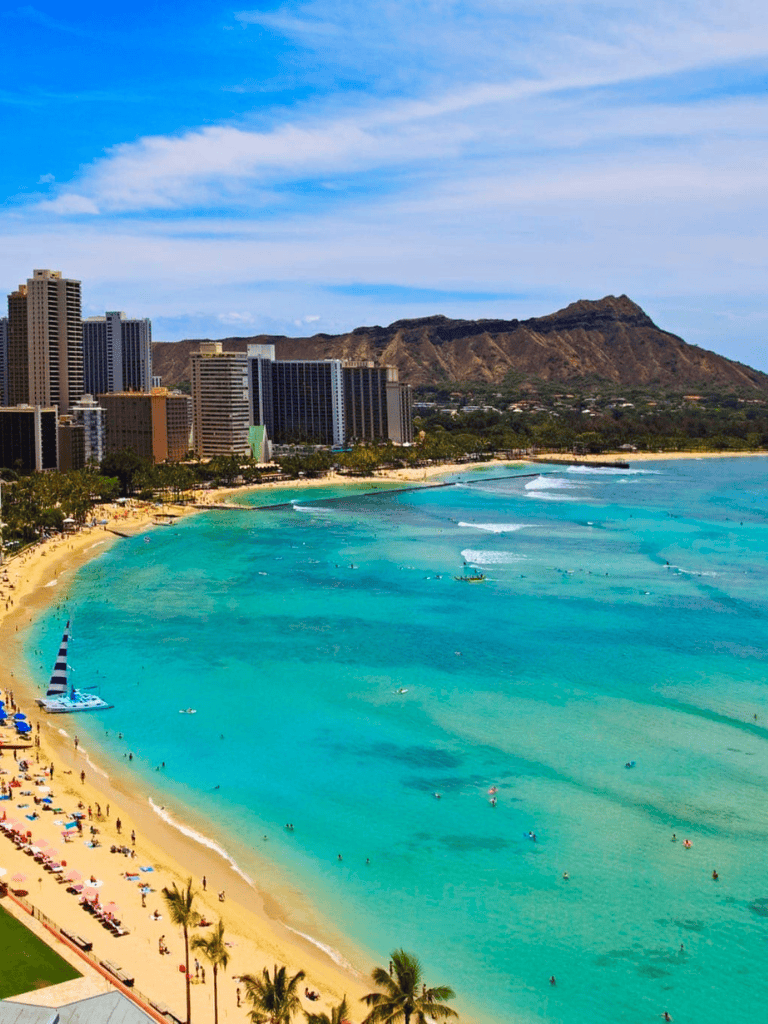 Beautiful Waikiki Beach with clear turquoise waters and high-rise city skyline on Oahu, Hawaii.