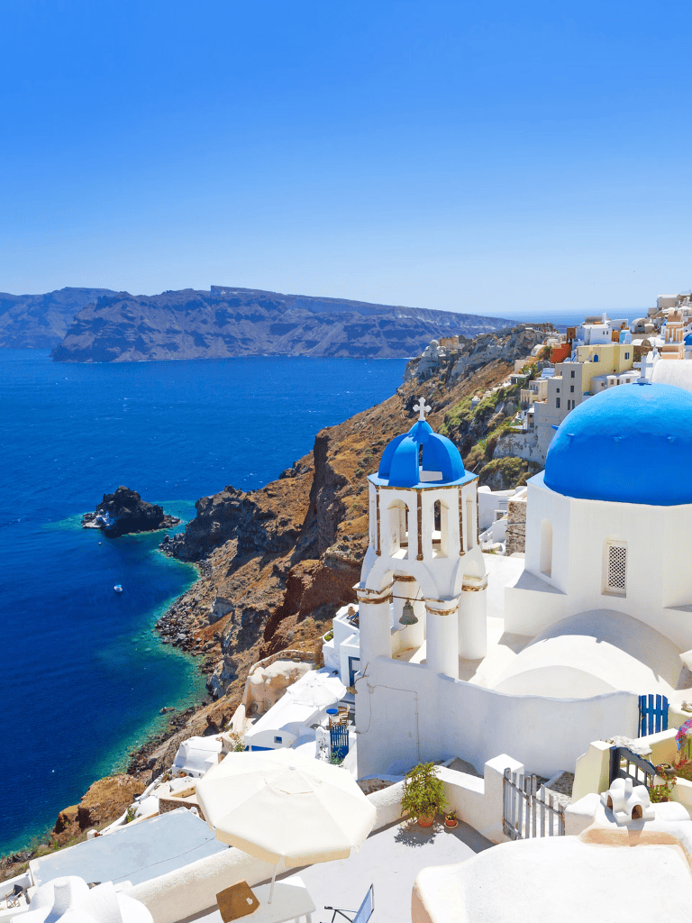 Vibrant Greek island coastal scenery with iconic white buildings and blue domes, stunning ocean views, and scenic cliffs.