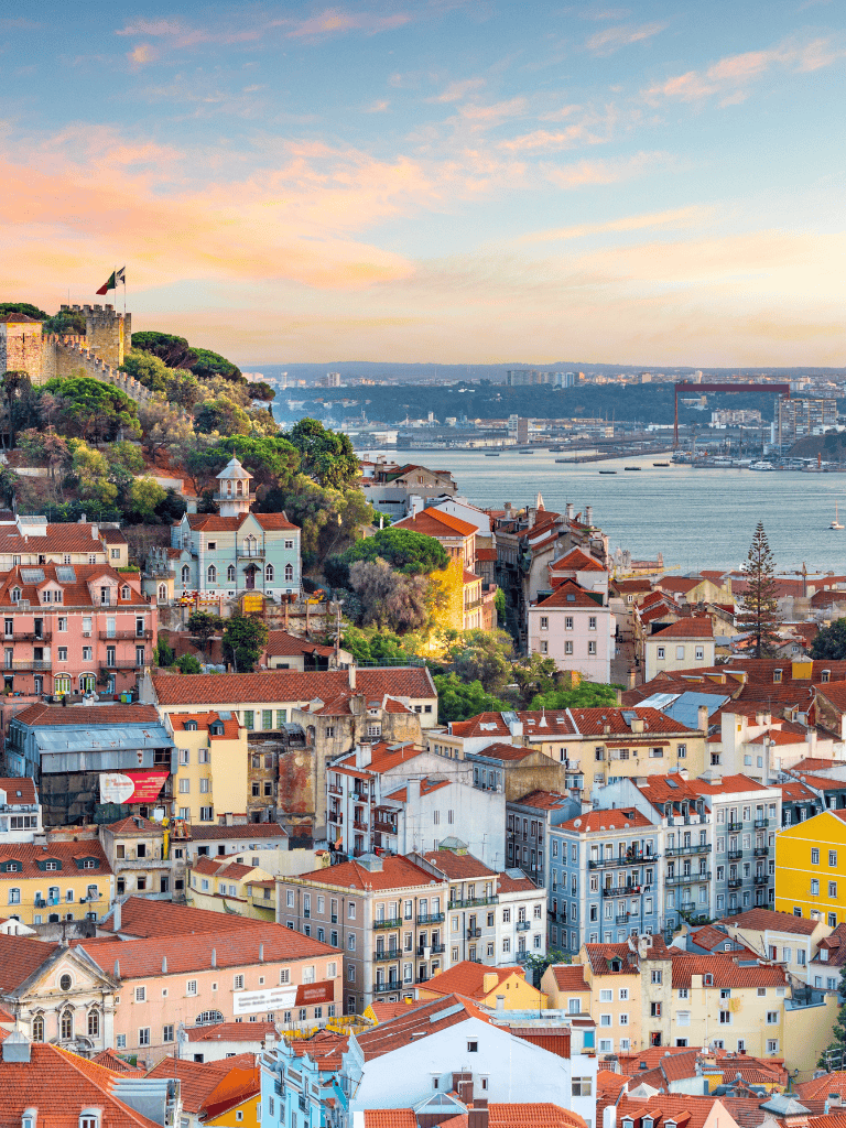 Colorful Lisbon cityscape with historic buildings and scenic river view during sunset.
