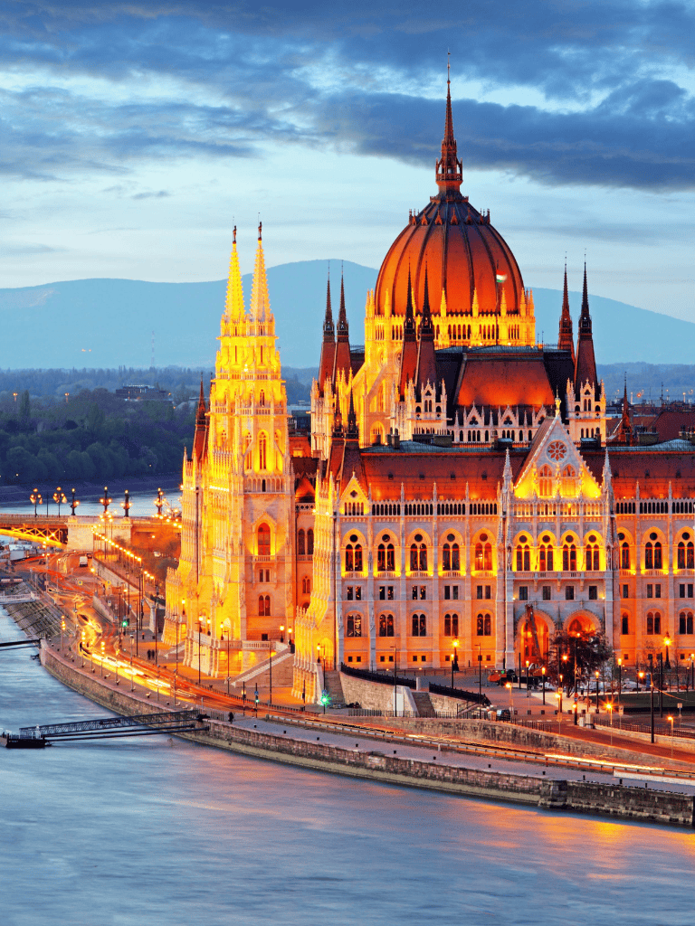 Magnificent illuminated Hungarian Parliament Building on the Danube River at sunset, showcasing Budapest’s iconic architecture.