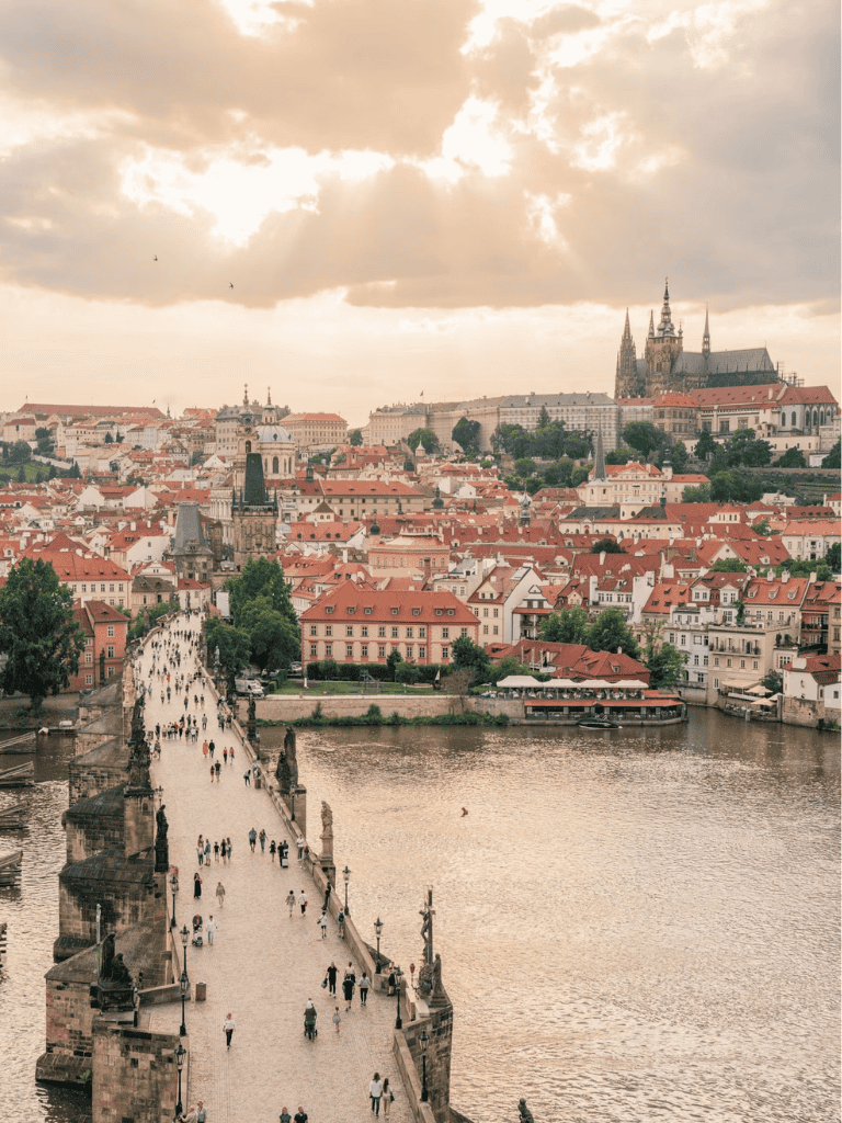 Panoramic view of historic Prague with Charles Bridge and Prague Castle under cloudy sky, scenic travel destination in Czech Republic.