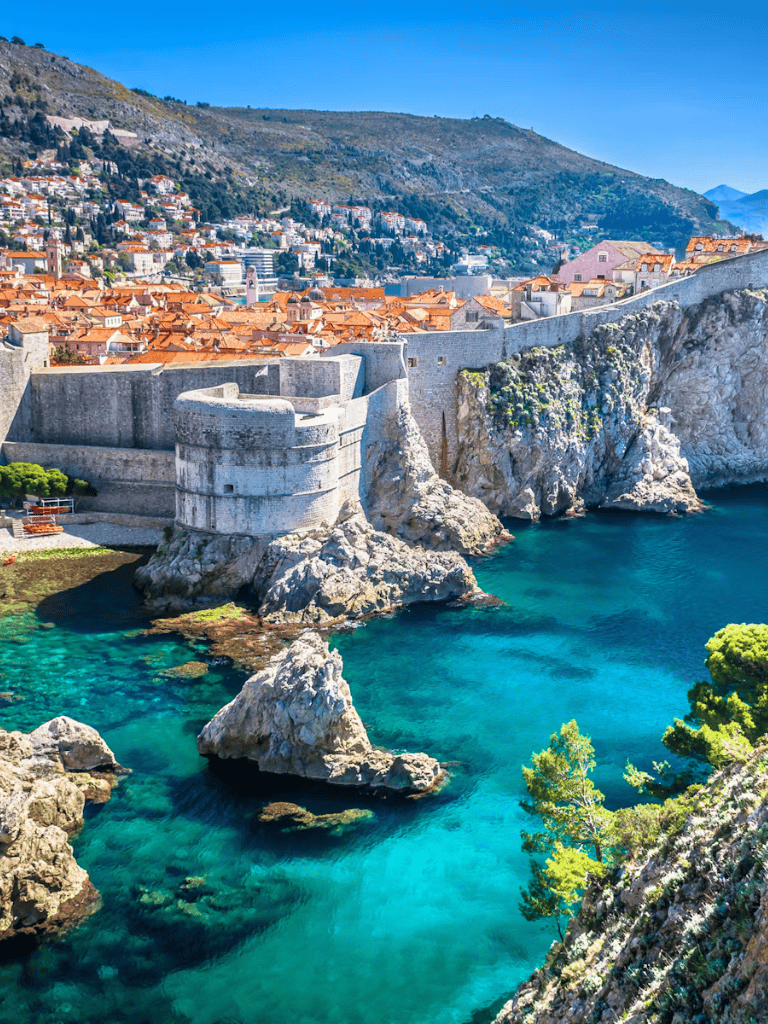 Ancient city walls along the Adriatic Sea in Dubrovnik, Croatia, with stunning turquoise waters and picturesque rooftops.