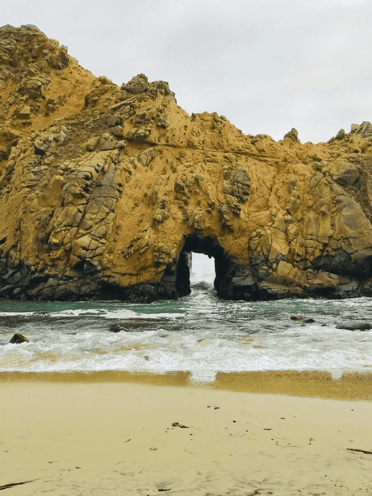Spectacular ocean arch rock formation at the beach under cloudy sky, perfect for travel and adventure photography.