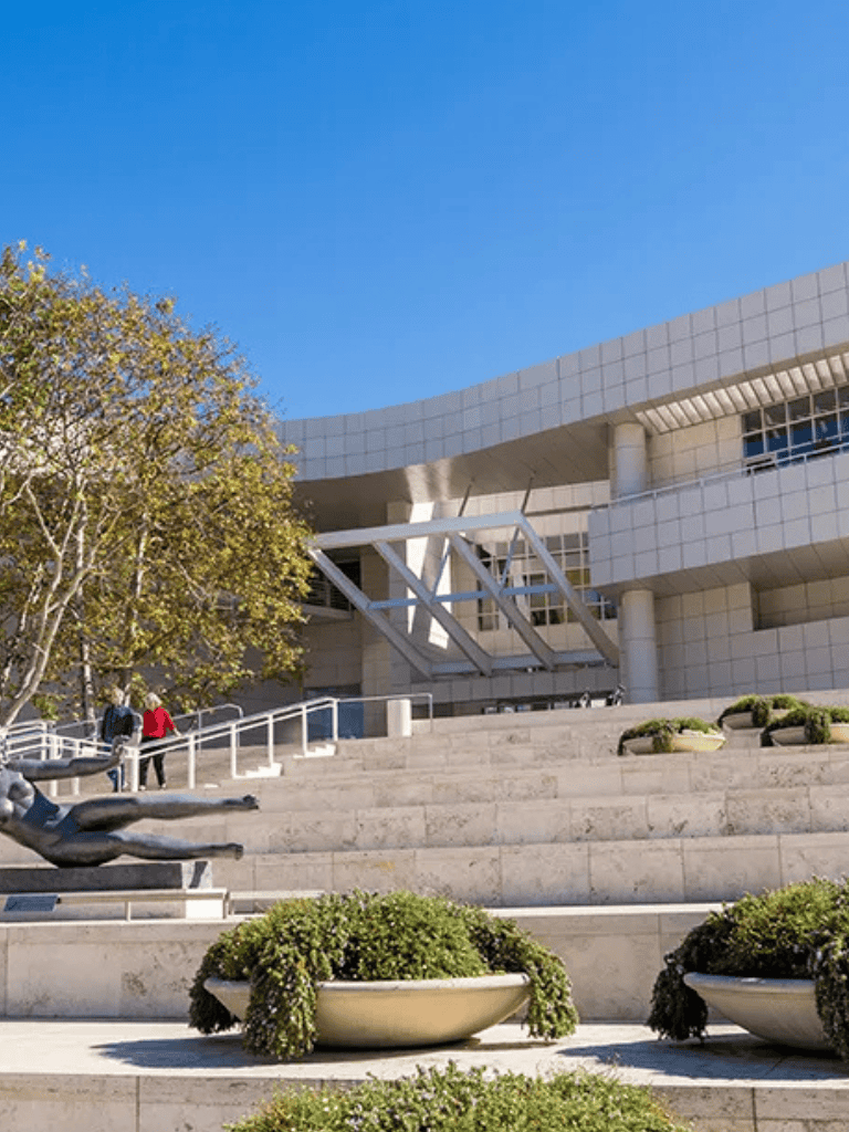 Modern architectural university building with sculptures and landscaped steps, sunny day, blue sky, QuestForDirections campus.