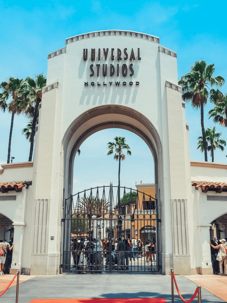 Universal Studios Hollywood entrance with palm trees and crowds.