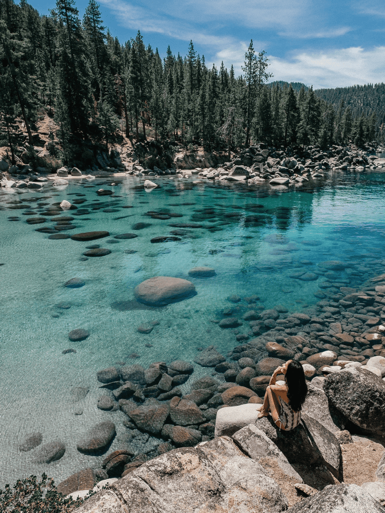 Serene mountain lake with clear blue water, surrounded by pine trees and rocky shores, ideal for outdoor adventures.